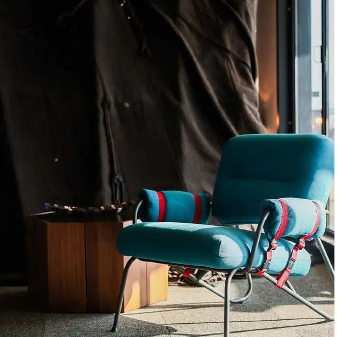 upholstered armchair with red accent straps.